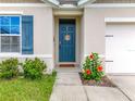 Welcoming front entrance with vibrant blue door, decorative shutters, and blooming hibiscus at 29746 Anahid Dr, Leesburg, FL 34748