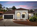 Charming single-story home with a two-car garage and inviting arched entryway at dusk at 641 Lakescape Ct, Orlando, FL 32828