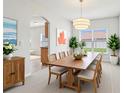 Airy dining room with long wooden table, chandelier, and neutral color palette at 670 Bluebill Ct, Poinciana, FL 34759