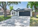 View of a bright white, single-story home with a two-car garage and a well-manicured lawn at 7646 Coconut Creek Ct, Orlando, FL 32822