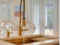 Close-up of a kitchen sink with a gold faucet, marble countertop, and integrated dish rack at 11721 Camden Park Dr, Windermere, FL 34786