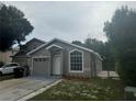 Charming single-story home with a gray exterior, updated landscaping, and an attached one-car garage at 1241 Cleveland Ave, Apopka, FL 32703