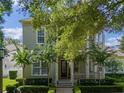 Charming two-story home with a covered porch and balcony surrounded by mature trees and manicured landscaping at 1438 Stickley Ave, Celebration, FL 34747