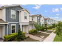 A row of modern townhouses with blue and white exteriors, landscaping and brick walkways at 14390 Orchid Island Dr, Orlando, FL 32827