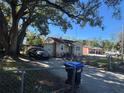 Charming bungalow-style home with mature trees, partially fenced yard, driveway and trash cans at 1500 43Rd St, Orlando, FL 32839