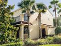 Inviting tan townhome boasting a balcony, palm trees, and lush greenery, creating a tropical and serene atmosphere at 2520 Bella Vista Dr, Davenport, FL 33897