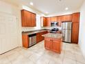 A kitchen with stainless steel appliances, granite countertops, tile flooring, and wood cabinets at 2520 Bella Vista Dr, Davenport, FL 33897