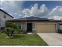 Charming single-Gathering house with a tan garage, lush green lawn, and solar panels, blending comfort with sustainability at 398 Citrus Isle Loop, Davenport, FL 33837