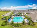 Beautiful community pool with blue lounge chairs surrounded by palm trees, and well-maintained lawns in a modern neighborhood at 3980 Gadwall Pl, Leesburg, FL 34748