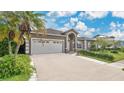Attractive home showcasing a spacious driveway, two-car garage, arched doorway, and lush, green front lawn at 5203 Jasmine Trace Ln, Kissimmee, FL 34758