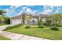 Well-maintained home featuring green lawn, mature landscaping, and solar panels on the roof, adding to energy efficiency at 5203 Jasmine Trace Ln, Kissimmee, FL 34758