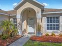 Welcoming front entry with covered porch, decorative columns, and manicured landscape at 703 Sunridge Woods Blvd, Davenport, FL 33837