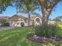 Charming single-story home featuring a well-manicured lawn, two car garage, and mature shade tree at 703 Sunridge Woods Blvd, Davenport, FL 33837