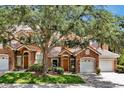 Charming townhome showcasing a stone facade, attached two-car garage, a neatly manicured lawn, and mature trees at 7521 Bay Port Rd # 12, Orlando, FL 32819