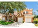 Charming townhome showcasing a stone facade, attached two-car garage, a neatly manicured lawn, and mature trees at 7521 Bay Port Rd # 12, Orlando, FL 32819