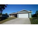 Exterior view of a single-story house with an attached garage and a concrete driveway at 943 Millenbeck Ave, Deltona, FL 32725