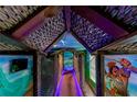 Unique hallway featuring custom artwork, thatched roofing and vibrant lighting, creating an immersive and playful atmosphere at 1421 Wexford Way, Davenport, FL 33896