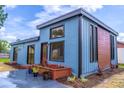 Modern blue home featuring a stylish exterior with a black roof, wood accents, and a charming front yard flower bed at 221 E Fern Dr, Orange City, FL 32763