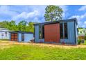 Exterior showing the side of the blue home with a brown accent section, and a detached shed at 221 E Fern Dr, Orange City, FL 32763