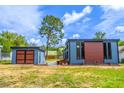 Side exterior view of the blue house and shed, framed by green grass and a blue, cloudy sky at 221 E Fern Dr, Orange City, FL 32763