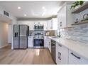 Bright modern kitchen with white cabinets, stainless steel appliances, and light wood floors at 221 E Fern Dr, Orange City, FL 32763