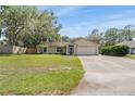 Single-story home with mature trees, green lawn, attached two-car garage and a concrete driveway at 3304 Vancouver Ave, Deltona, FL 32738