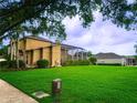 Spacious backyard features a large grassy area, mature trees, and a screened enclosure at 357 Fairway Pointe Cir, Orlando, FL 32828