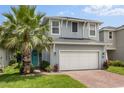 Charming two-story home with a white garage door, brick driveway, and a beautiful aqua-colored front door at 3804 Corona Ct, Sanford, FL 32773