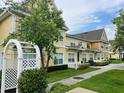 Exterior community view with townhomes featuring yellow siding, green spaces, sidewalks, and mature trees at 4010 Santa Maria Dr # 106, Kissimmee, FL 34741