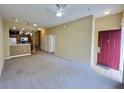 A spacious living room featuring neutral carpet, beige walls, ceiling fan, and stairs to the upper level at 4010 Santa Maria Dr # 106, Kissimmee, FL 34741