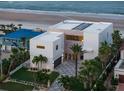 Aerial view of modern home with unique architecture, lush landscaping, and direct beach access at 4647 Van Kleeck Dr, New Smyrna Beach, FL 32169