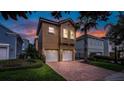 Inviting two-story home with a brick driveway, manicured landscaping and attached two-car garage at 7411 Excitement Dr, Reunion, FL 34747