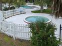 Inviting community hot tub and pool area surrounded by a white picket fence and lush tropical landscaping at 7900 S Orange Blossom Trl # 1099, Orlando, FL 32809