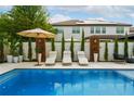 Beautiful pool surrounded by comfortable lounge chairs, landscaping and a large umbrella at 7974 Chilton Dr, Orlando, FL 32836