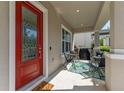 Inviting front porch with outdoor seating, a red front door and a charming welcome mat at 9348 Meadow Hunt Way, Winter Garden, FL 34787