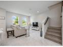 Bright living room boasting white marble floors, natural light, and modern furnishings with easy stair access at 10221 Highline Crest St, Orlando, FL 32832
