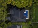 Aerial view of a luxury home with a dark roof, bordered by lush trees, with a blue pool and spa in the backyard at 1211 Munster St, Orlando, FL 32803