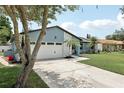 Well-maintained home showcasing a clean driveway, two-car garage, and lush green lawn on a sunny day at 1360 Gladiolas Dr, Winter Park, FL 32792