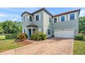 Beautiful home featuring a brick driveway, two-car garage, and manicured landscaping at 235 Aidans Lndg, Haines City, FL 33844