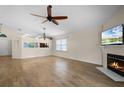 Open-concept living room with a fireplace, wood floors, a ceiling fan, and lots of natural light at 3055 Dellcrest Pl, Lake Mary, FL 32746