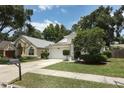 A suburban home with a lush green lawn, mature trees, a two-car garage, and a charming exterior design at 5165 Mystic Point Ct, Orlando, FL 32812