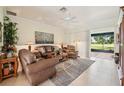 Comfortable living room featuring leather furniture, a ceiling fan, and sliding glass doors leading to the lanai at 5453 Grove Mnr, Lady Lake, FL 32159