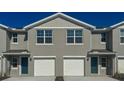 Townhouse exterior with gray siding, white trim, dual garages and blue front doors at 6615 Leo Ln, St Cloud, FL 34773