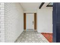 Inviting front porch with decorative tile flooring, a white brick wall, and a modern-style front door at 7124 Turquoise Ln, Orlando, FL 32807