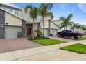 Modern townhomes feature stone accents, attached garages, and well-manicured lawns at 877 Ocean Course Ave, Davenport, FL 33896