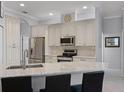 Bright kitchen featuring white cabinets, stainless steel appliances, and granite countertops with bar seating at 1124 Hidden Blf, Clermont, FL 34711