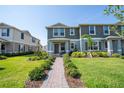 Inviting two-story townhome with lush green lawn and neatly trimmed bushes lining the brick-paved walkway at 13452 Sagestone Dr, Winter Garden, FL 34787