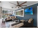 Cozy screened-in porch featuring comfortable seating, a ceiling fan, and a mounted TV for outdoor entertainment at 1610 Owl Ridge Ct, Apopka, FL 32712