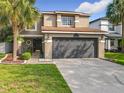 Inviting home featuring a well-manicured lawn, mature palm trees, and a two-car garage at 1803 Meadow Pond Way, Orlando, FL 32824