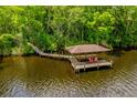 Waterfront dock features a covered sitting area with two red Adirondack chairs at 20 Twelve Oaks Trl, Ormond Beach, FL 32174